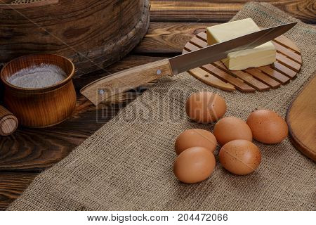Ingredients for homemade bread over burlap and wooden broun background knife in butter