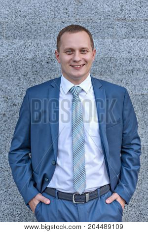 portrait of a young serious smiling businessman in grey blue suit