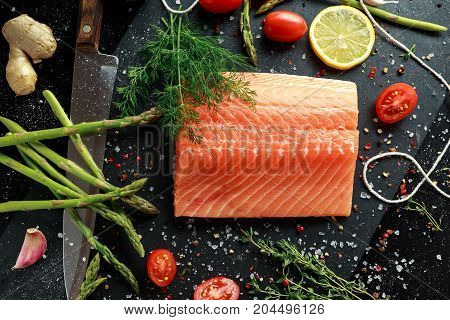Fresh raw salmon fillet steak with aromatic herbs, spices.