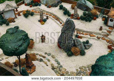 Miniature houses, toy landscape objects on the sand. Sand therapy. Toy landscape layout on sand from toy items