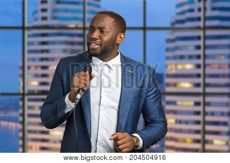 Singing man on scyscraper background. Evening live perfomance of afro american artist. Talanted jazz vocalist.