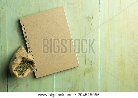 Book and mung bean in sack on wooden of pastal color copy space