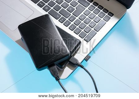 Two external or portable hard drive (HDD) connected to laptop on blue table