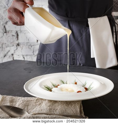 Waiter pouring broth to mushroom cream soup. Original restaurant serving of delicacy meal, copy space