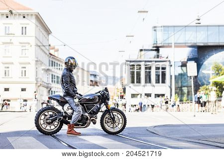 Cool looking motorcycle rider on custom made scrambler style cafe racer in the city
