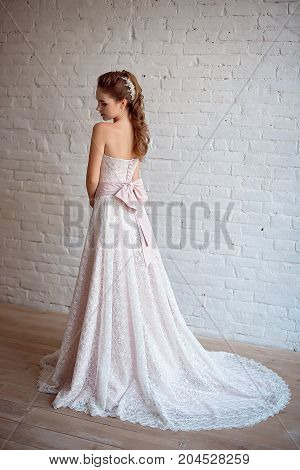 Full-length portrait of Beautiful luxurious female model with medium brown hair in a long white wedding dress in the room. Bridal clothes concept. Stylish wedding dress.