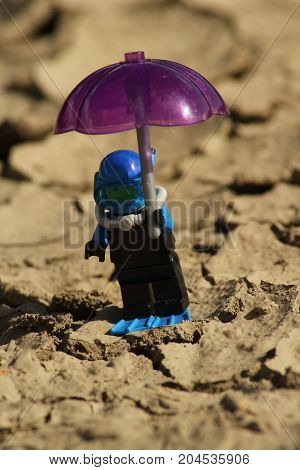 Figurine scuba diver with umbrella on parched ground/This is a detail of parched ground and figurine scuba diver with umbrella.
