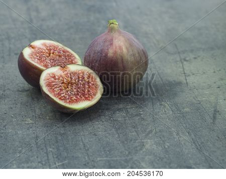 close up one and two half of fresh ripen fig on grey textured background
