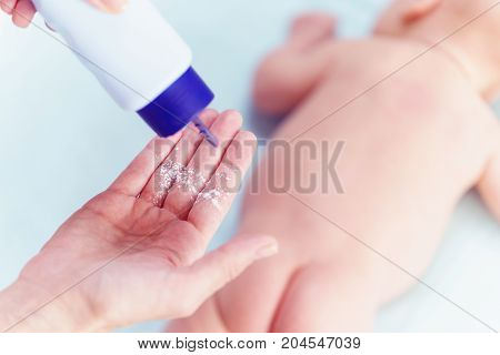 Mom Applying Talc Powder From Plastic Tube To The Baby Body