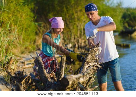 Father and Teen girl with sabersaw is sawing a logs.