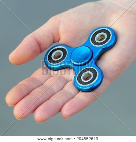 Blue metal popular fidget spinner toy on the palm of your hand take it