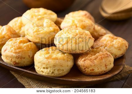 Hungarian traditional Cheese Pogacsa savory baked bread-like pastry on wooden plate photographed with natural light (Selective Focus Focus on the front of the first three pastries)