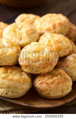 Hungarian traditional Cheese Pogacsa savory baked bread-like pastry on wooden plate photographed with natural light (Selective Focus Focus on the front of the first pastries on the top)