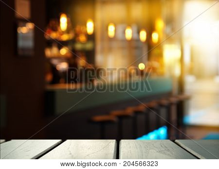 top of wood table with blur light of pub cafe and bar in the dark night