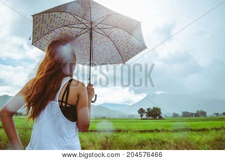 Asian women travel relax in the holiday. Women stand in rain umbrellas. On the meadow During the rainy season.Thailand