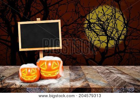 Blackboard with easel on grunge plank wooden and pumpkin with smoke on table top at spooky dead tree and full moonHalloween invitation cardTemplate mock up for display or montage of product.