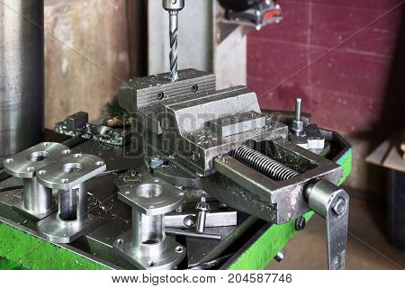 Drilling machine. The drill bit is installed in the drill chuck. Machine vice, metalworking shop.