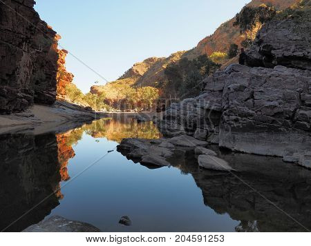 Reflections in the dark waters of Ormiston Gorge with red glowing cliffs in the evening sun Northern Territory Australia 2017