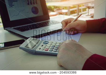 hand working with finances about cost and calculator business strategy diagram report and laptop computer on desk at home office income and expenses plan money cost savings and business concept