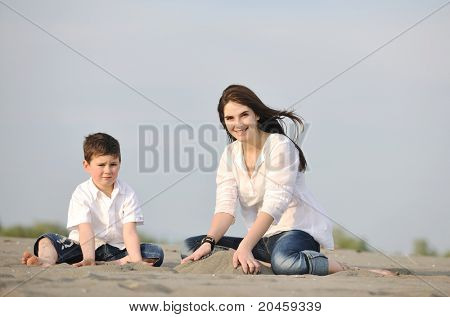 Happy young Mother und Sohn entspannen und spielen ind Sand Spiele am Strand im Sommer