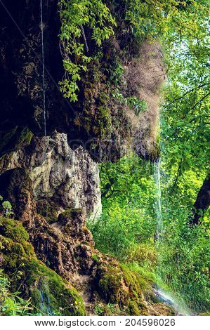 Photo of little beautiful waterfall flowing in cave