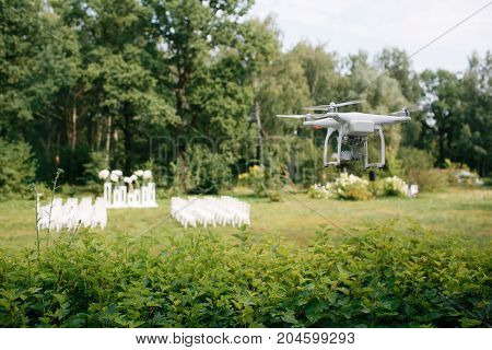 Videography wedding ceremony from the air a small spy quad copter scout drone flying through the trees in a forest.