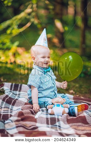 Little infant baby boy 1year kid on a plaid in park. Summer sunset. Copy space