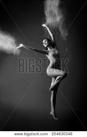 Athletic dancer in cloud of powder on the scene.