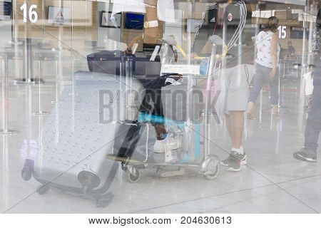 ROISSY FRANCE - August 16 2017. Airport luggage Trolley with suitcases unidentified man woman walk in the airport. Blur motion double exposure.
