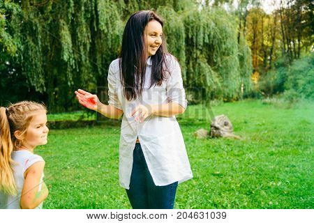 mother with daughter play with holi paints in city park