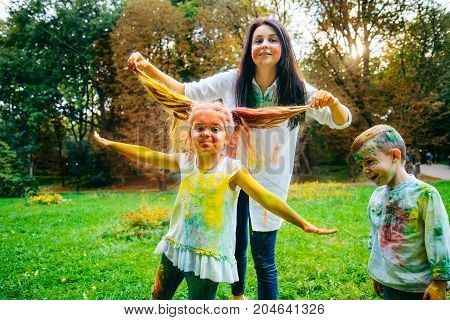 mother son and daughter full around with holi paints in city park