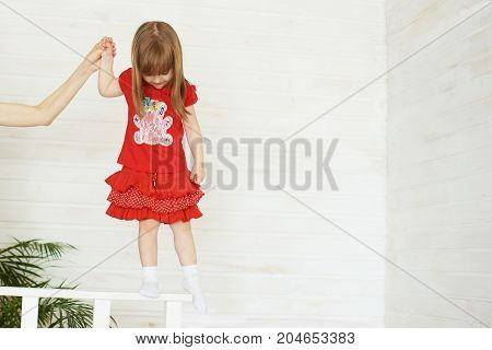 Young cute girl in red standing on railing.