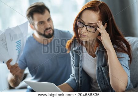 I need to work. Sad unhappy cheerless woman holding her temple and trying to focus on her work while listening to her boyfriend