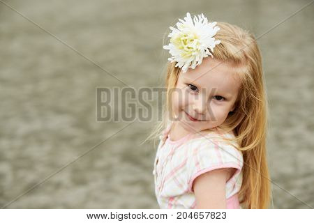 Young girl with white flower. Smiling blond.