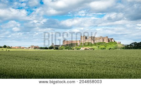 Bamburgh village and Castle, England. A view over the Northumberland countryside in north-east England towards the village of Bamburgh dominated by its famous landmark castle.