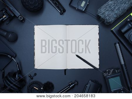 Compisition with field audio recorder card case windsheild and shotgun microphone and other stuff on the dark background