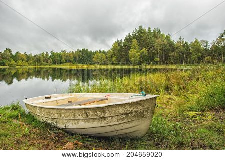 White boat at the lake with rainy framatic clouds.