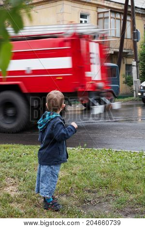 Little boy red fire truck on road