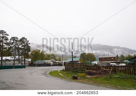 Altai village with fog on mountain. Green grey