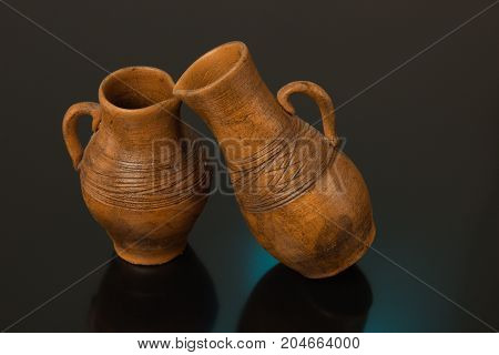 Ceramic pots with carved pattern on a black background with blue and yellow light