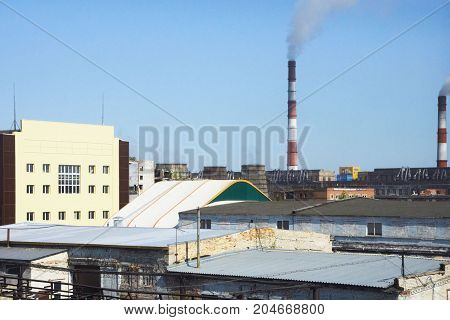 Roof. Industrial architecture. Pipe with smoke. Blue sky