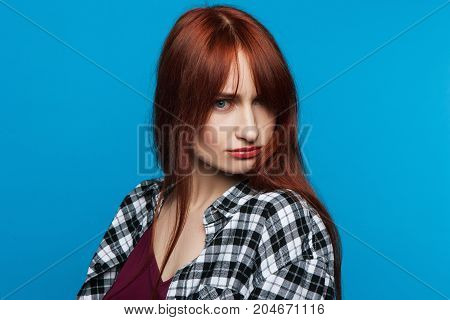 Offended young woman on blye background. Insult conversation. Upset and distrustful female, bad news for pretty girl