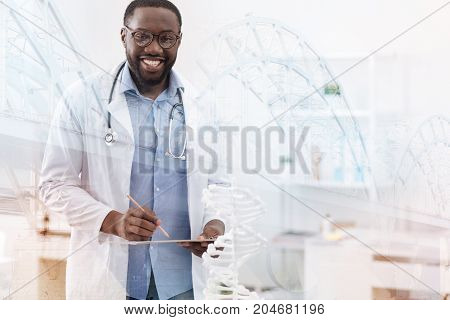 Appropriate medical care. Waist up of kind hearted positive doctor standing in front of you and smiling