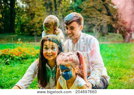 happy family in the prak playing with holi paints