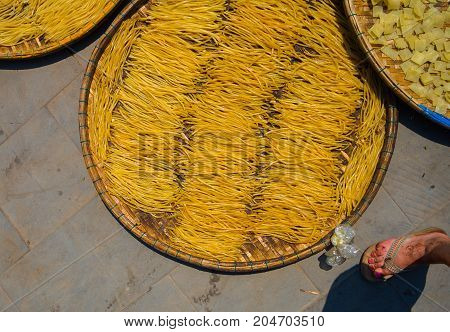 HOIAN, VIETNAM, SEPTEMBER, 04 2017: Vietnamese people dry noodles in the sun over the pavement in Hoian in Vietnam.