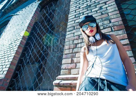 A beautiful young Hip Hop Rapper girl with Headphones in a urban environment.
