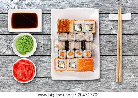 Japanese food restaurant delivery - sushi maki, unagi and roll platter set isolated on gray wood background, above view