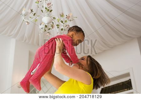 happy family. Mother throws up baby, playing at home.