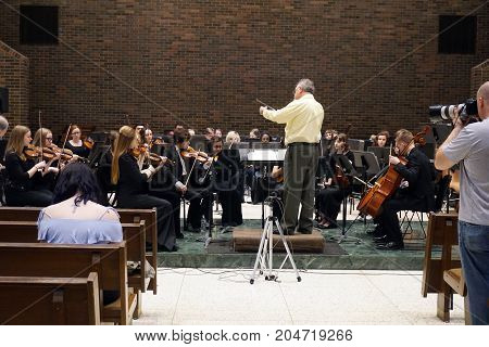 ROMEOVILLE, ILLINOIS / UNITED STATES - MAY 21, 2017: Dr. Lawrence Sisk conducts the Metropolitan Youth Symphony Orchestra (MYSO) in a dress rehearsal prior to a concert in Borromeo Hall at Lewis University.