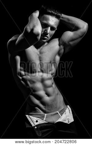 young handsome man with bare torso and sexy muscular body in trausers in studio